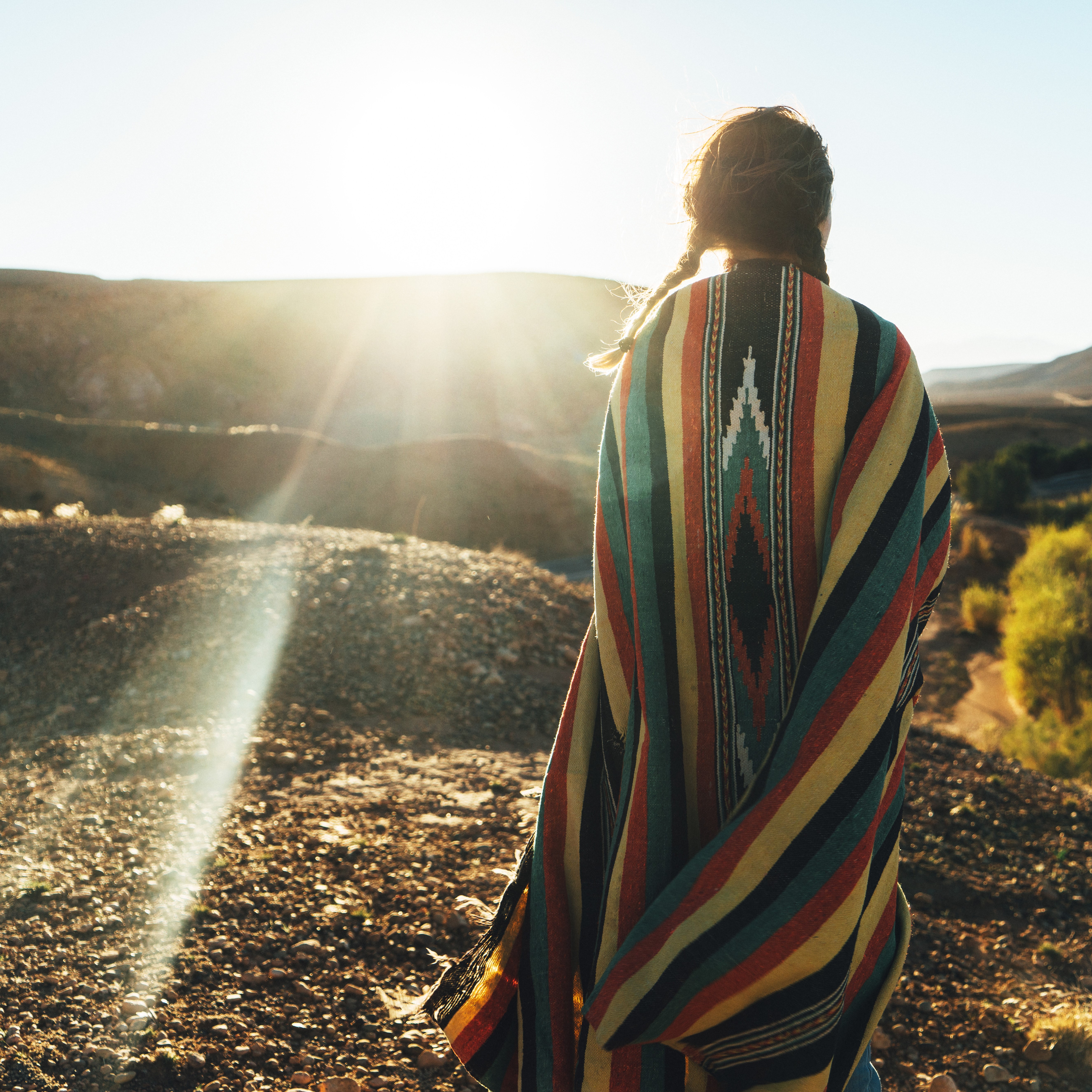 Woman draped in a woven  blanket facing the sun